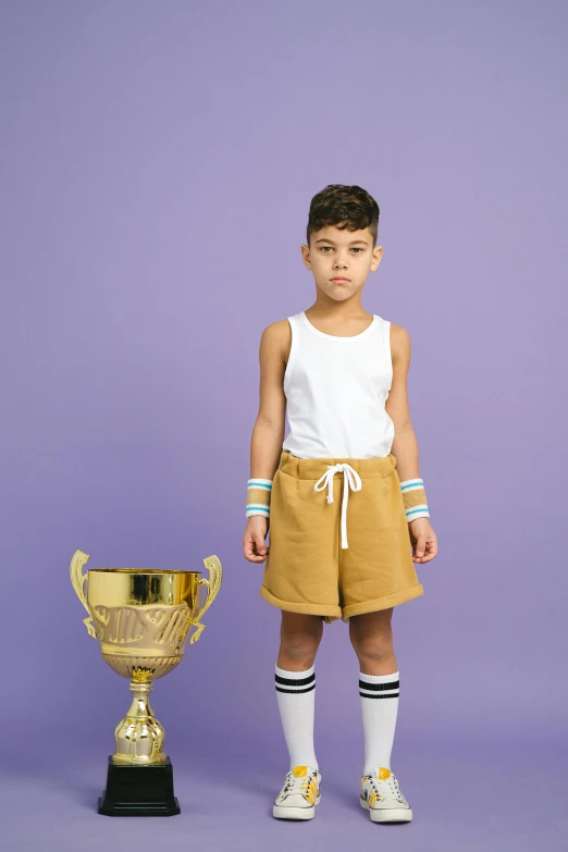 a young boy standing next to a trophy, inspired by The Family Circus, dribble contest winner, bra and shorts streetwear, caramel. rugged, spiked wristbands, curated collections