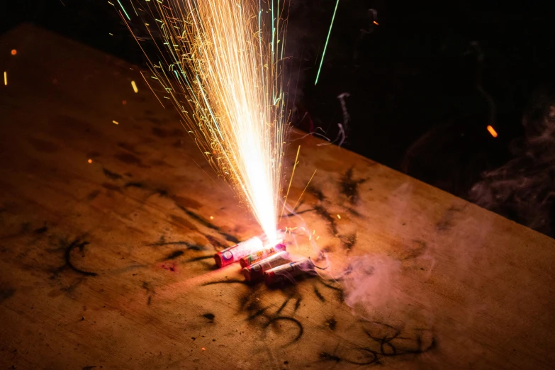 a close up of a fire with sparks coming out of it, by Daniel Lieske, pexels contest winner, shock art, on a wooden table, laser cut, celebrating a birthday, booster flares