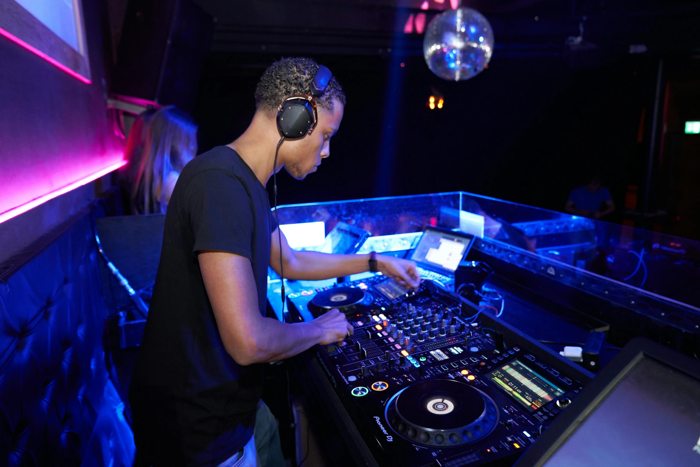 a man that is standing in front of a dj, during the night