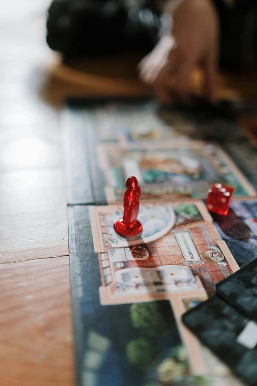 a person playing a board game on a wooden floor, by Kristian Zahrtmann, unsplash, mansions of madness, game icon, thumbnail, multiple stories