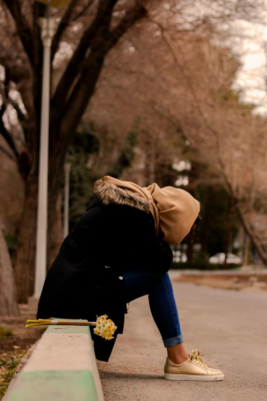 a person sitting on a curb with a skateboard, a picture, by Maryam Hashemi, unsplash, romanticism, woman crying, holding a gold bag, iran, winter season