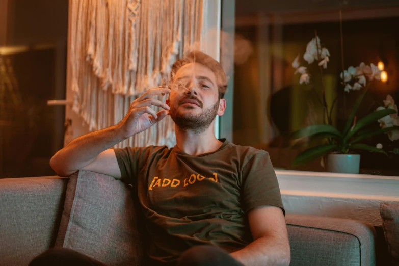 a man sitting on a couch smoking a cigarette, inspired by Elsa Bleda, pexels contest winner, neo-dada, wearing a marijuana t - shirt, avatar image, charlie cox, instagram picture