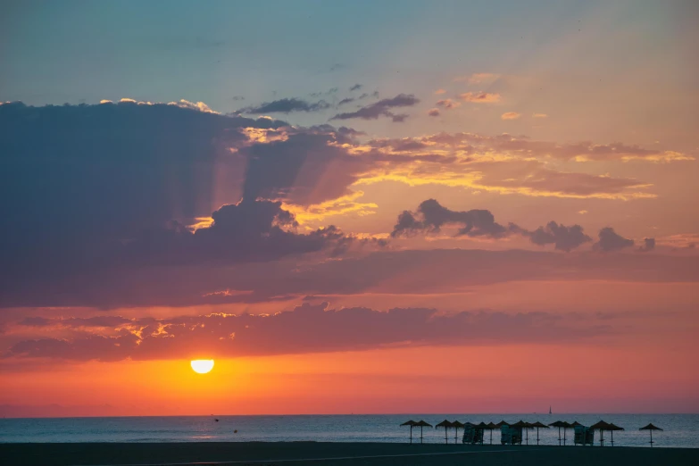 a couple of umbrellas sitting on top of a sandy beach, by Jan Tengnagel, pexels contest winner, sunset panorama, seville, fine art print, multiple suns