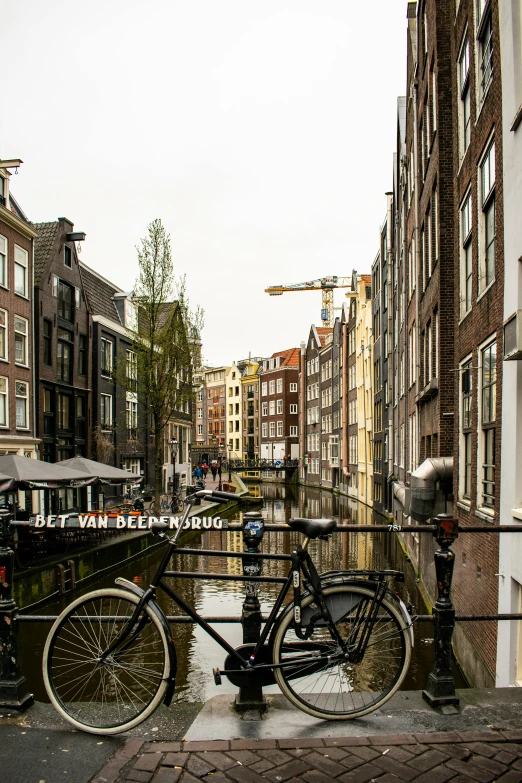 a bicycle parked on a bridge over a canal, the neat and dense buildings, dutch masters, & a river, alleys