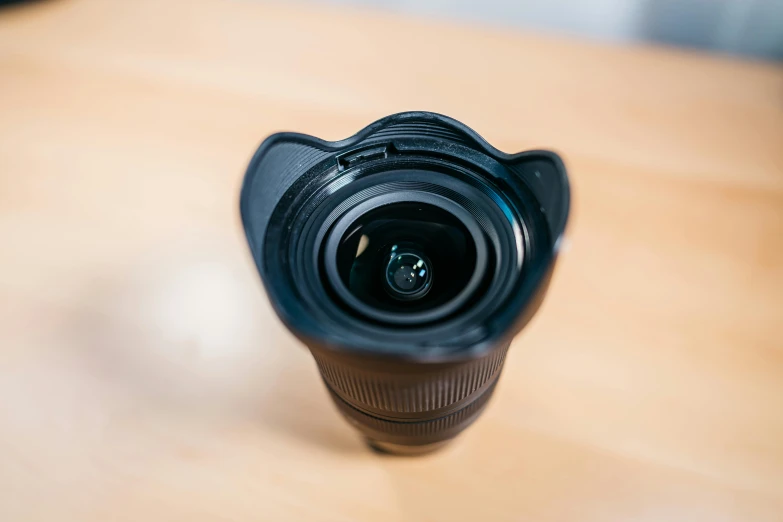 a camera lens sitting on top of a wooden table, top lid, 12mm wide-angle, photograph taken in 2 0 2 0, curled perspective