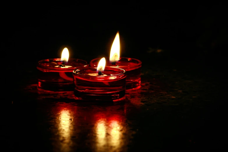 a couple of red candles sitting on top of a table, during the night