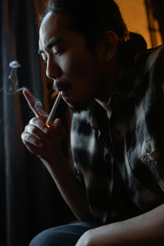 a man smoking a cigarette in a dark room, a portrait, inspired by Liam Wong, unsplash, 千 葉 雄 大, personification of marijuana, with a cool pose, asian human