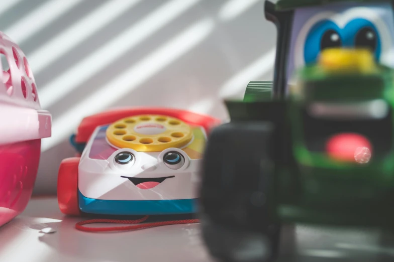 a number of toys on a table near one another, unsplash, photorealism, telephone, smiling, vehicle, fisher price