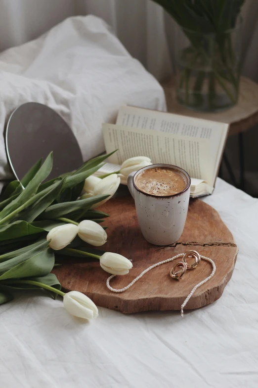 a cup of coffee and some white tulips on a bed, by Lucia Peka, trending on unsplash, romanticism, wooden jewerly, iced latte, storybook style, overflowing