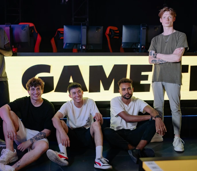 a group of young men sitting next to each other, a portrait, by Sam Black, gaming chair, server in the middle, fame, official store photo