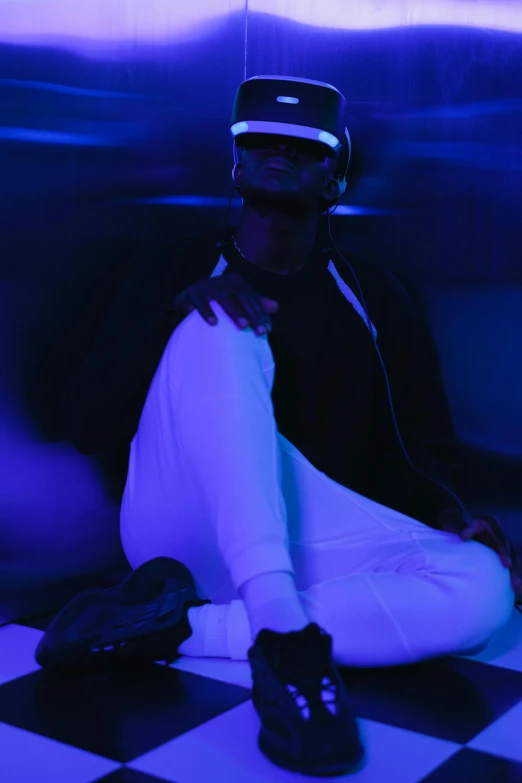a man sitting on a checkered floor wearing a virtual reality headset, a hologram, inspired by Zhu Da, trending on pexels, afrofuturism, moody blue lighting, ski mask, an all white human, dark visor covering face