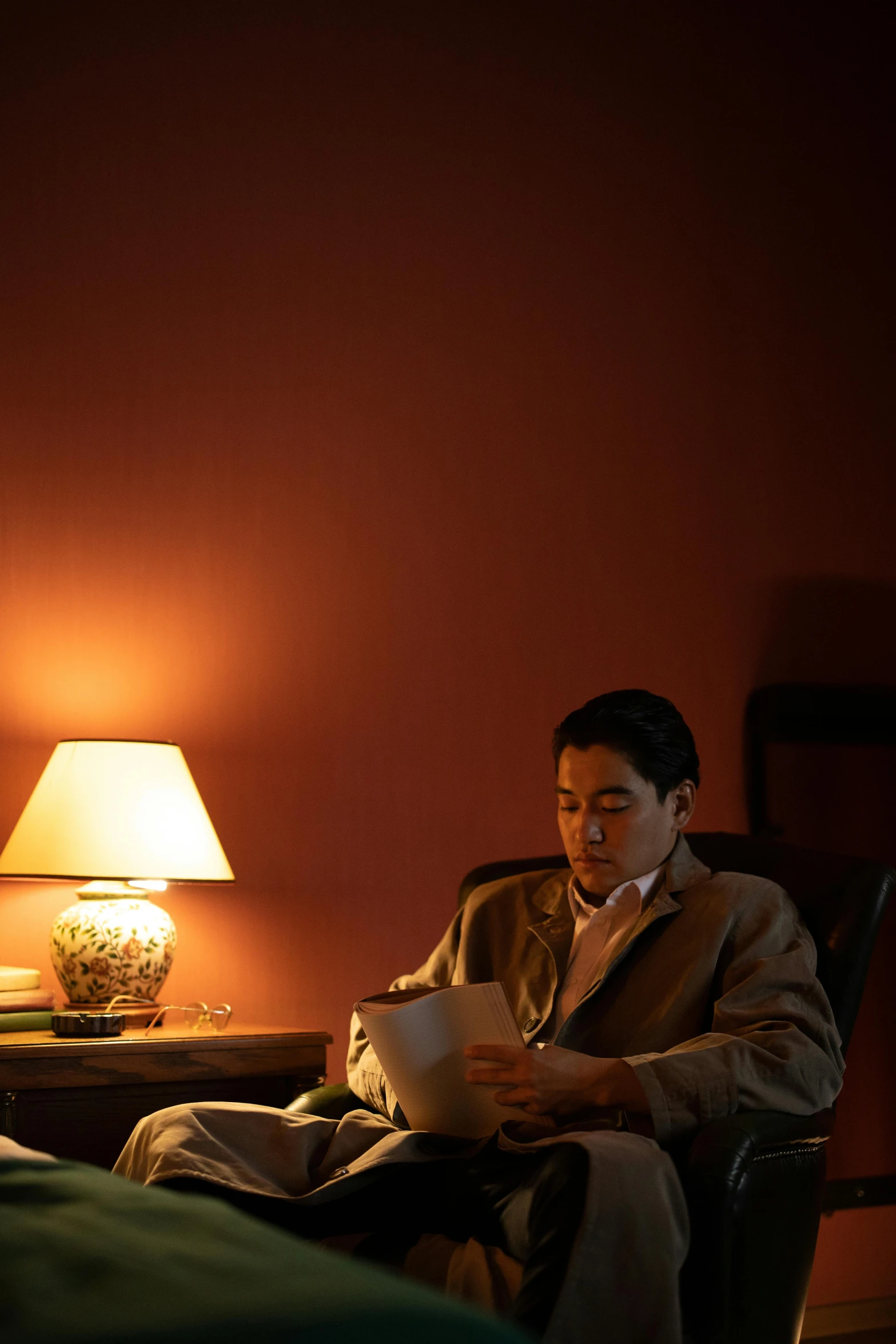 a man sitting in a chair reading a book, inspired by Hideyuki Kikuchi, brown atmospheric lighting, john cho, soft lighting |, complementary lighting