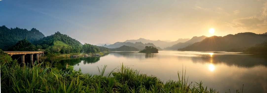 a large body of water next to a forest, by Reuben Tam, pexels contest winner, sumatraism, laos, in the morning light, mountains and lakes, panoramic shot