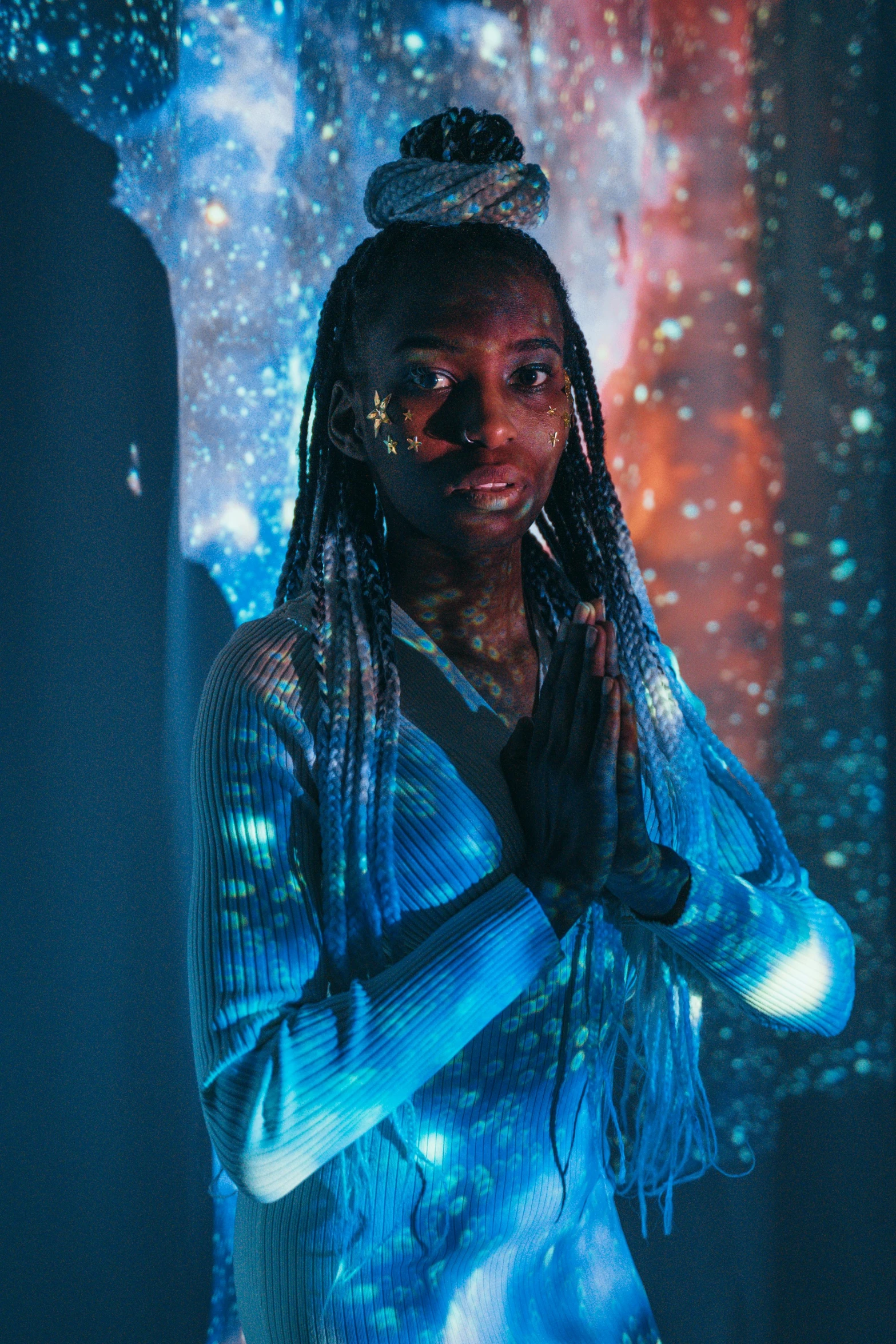 a woman with dreadlocks standing in front of a mirror, a hologram, trending on pexels, afrofuturism, with glowing blue lights, holding a galaxy, androgynous person, ( ( dark skin ) )