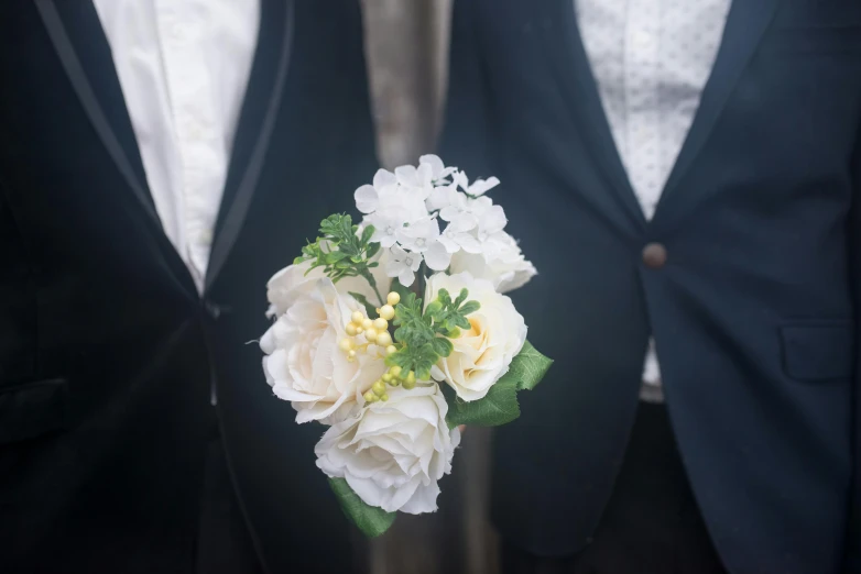 a man in a tuxedo holding a bouquet of flowers, by Nina Hamnett, unsplash, two young men, very pale, lgbt, with a white