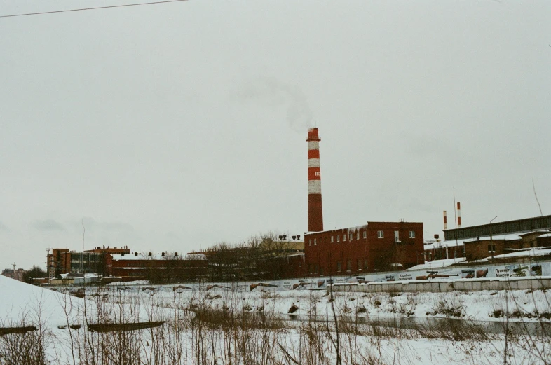 a snow covered field with a factory in the background, an album cover, inspired by Elsa Bleda, unsplash, nuclear art, f 1.4 kodak portra, russian city, chimney, old color photograph
