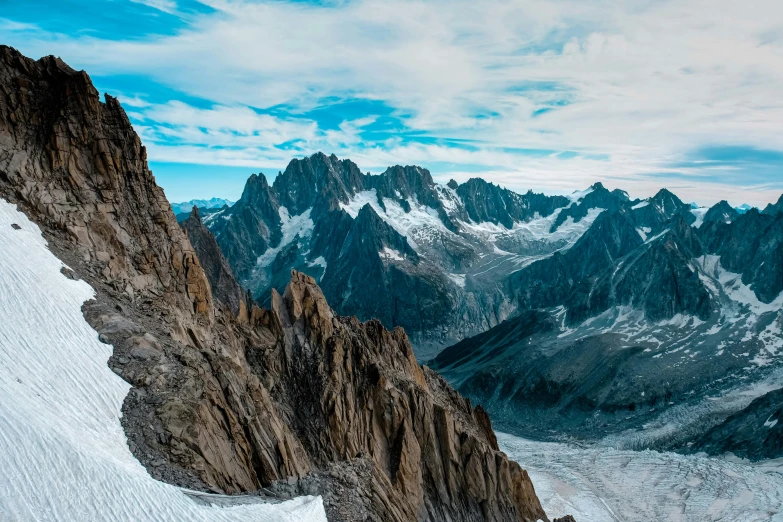 a man standing on top of a snow covered mountain, a matte painting, by Pierre Mion, pexels contest winner, structural geology, high angle vertical, majestic spires, panoramic