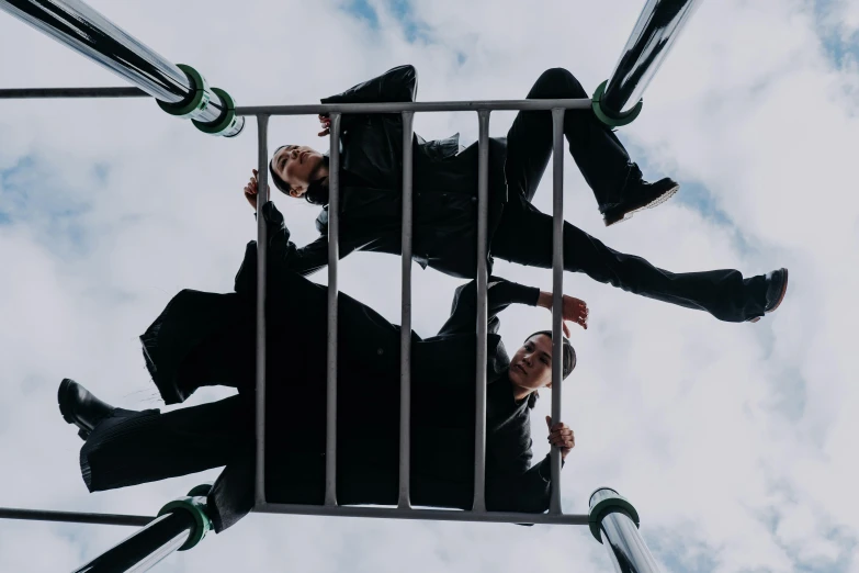 a couple of men standing on top of a metal structure, an album cover, unsplash, playground, mid air shot, two men in black, liam brazier