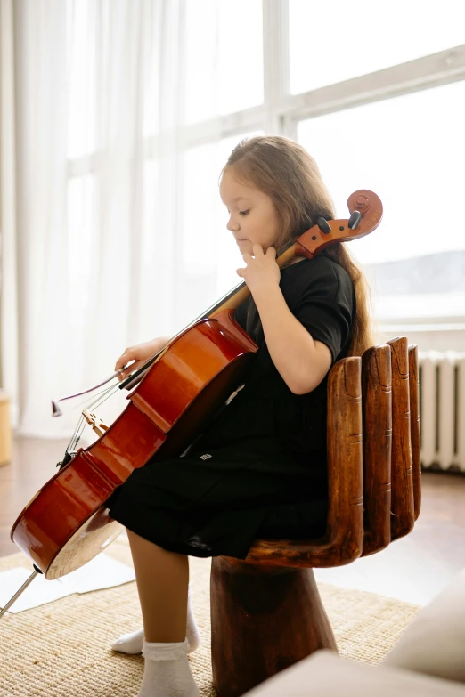 a woman sitting in a chair playing a cello, pexels contest winner, 5 years old, 💣 💥💣 💥, good posture, greta thunberg