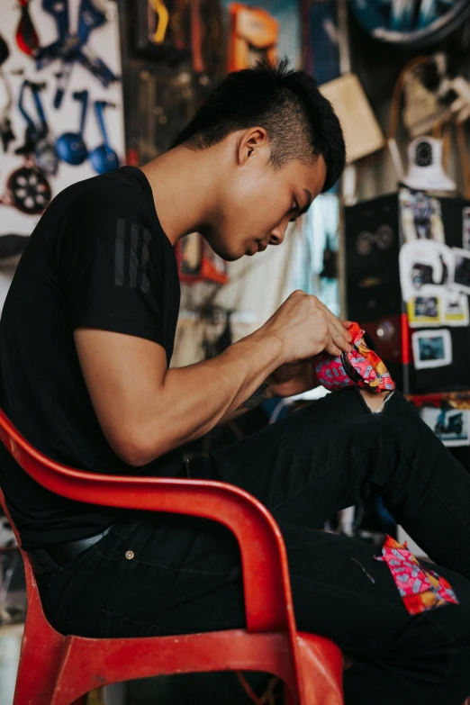 a man sitting on top of a red chair, wearing nike air mags, crafting, kenny wong x pop mart, with highly detailed