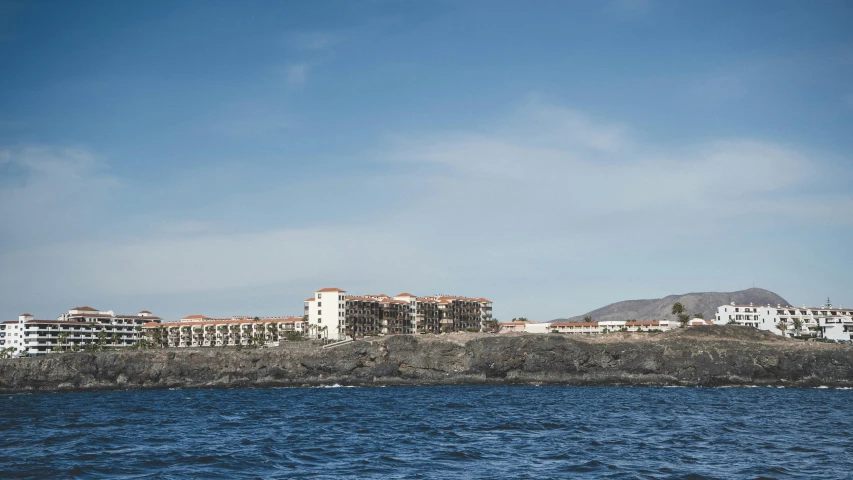 a large body of water with buildings in the background, quixel megascans, view from the sea, barcelo tomas, black rocks