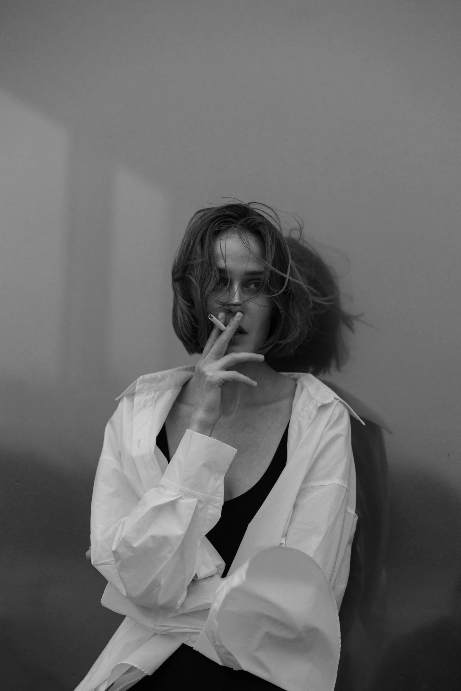 a woman sitting on a couch smoking a cigarette, a black and white photo, unsplash, realism, joey king, clothed in white shirt, nadezhda tikhomirova, very aesthetic!!!!!!