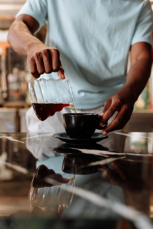 a man pouring something into a cup on top of a stove, pexels contest winner, in a coffee shop, jamaica, glossy surface, thumbnail