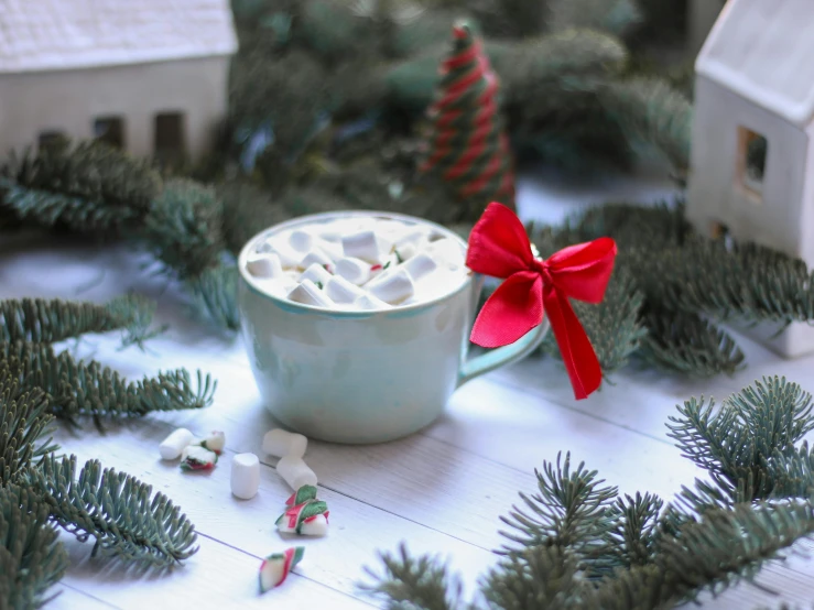 a cup of hot chocolate sitting on top of a table, by Emma Andijewska, pexels contest winner, hurufiyya, gingerbread candy village, background image, ribbon, anna nikonova aka newmilky