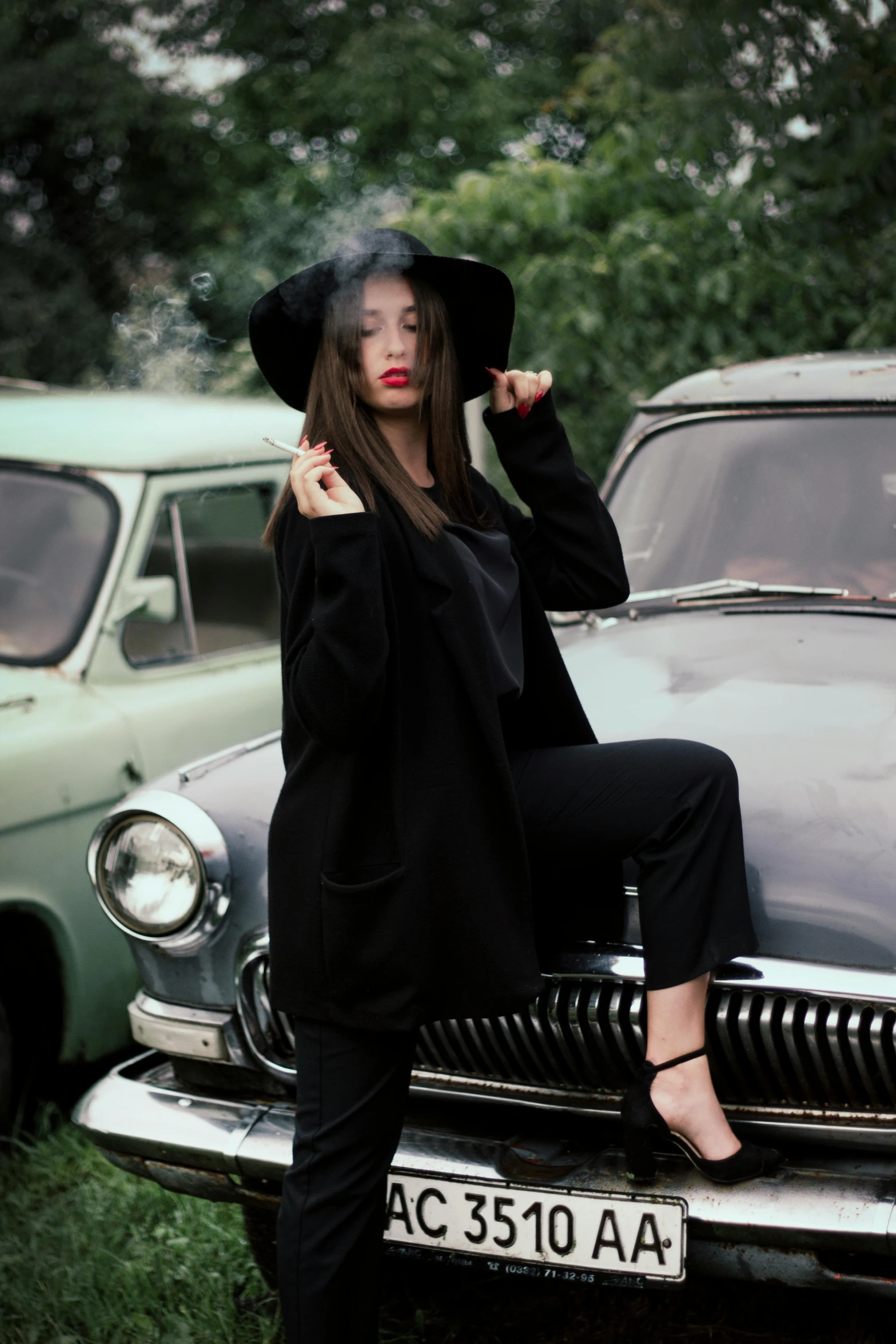 a woman sitting on the hood of a car, inspired by Evaline Ness, pexels contest winner, auto-destructive art, wearing causal black suits, anna nikonova aka newmilky, black pointed hat, instagram picture