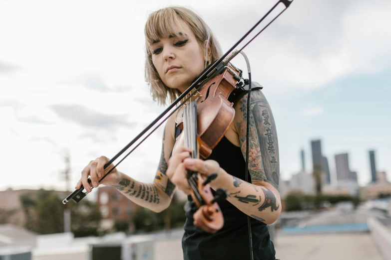 a woman playing a violin on top of a roof, by Winona Nelson, unsplash, bauhaus, with tattoos, beth cavener, holding a bow, avatar image