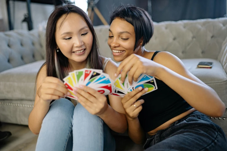 two women sitting on a couch playing cards, inspired by Aquirax Uno, trending on unsplash, rainbow colored, teenage girl, avatar image