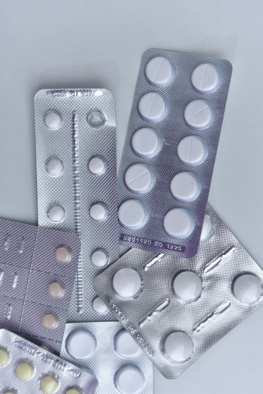 a bunch of pills sitting on top of a table, by Aileen Eagleton, plasticien, medical labels, white and silver, panels, grey