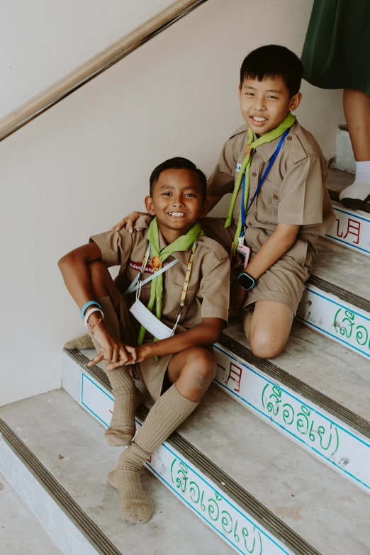 a couple of young boys sitting on top of a set of stairs, pexels contest winner, happening, girl wearing uniform, thailand, with brown skin, boy scout troop