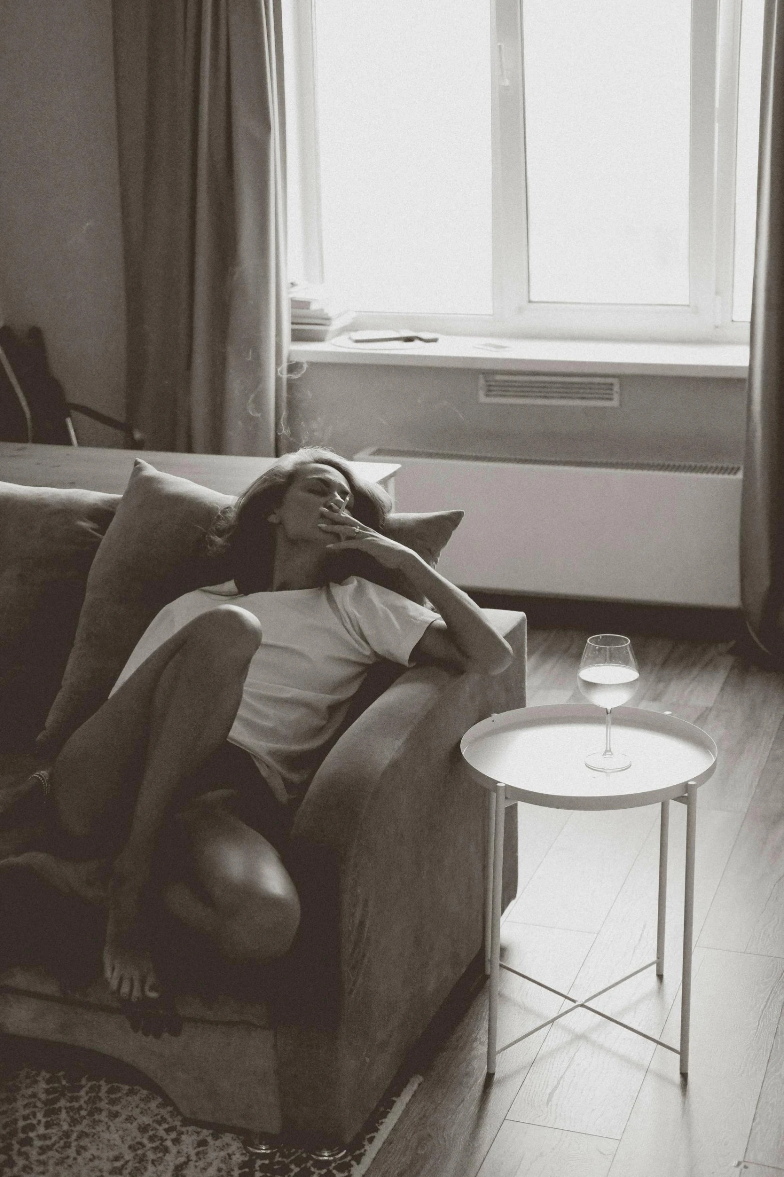 a man laying on a couch in a living room, a black and white photo, by Adam Marczyński, pexels contest winner, renaissance, drunk woman, sun down, beautiful lonely girl, woman crying