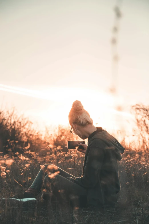 a person sitting in a field with a laptop, a picture, unsplash contest winner, aestheticism, bird on his shoulder, sunfaded, a blond, ((sunset))