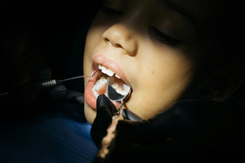 a close up of a person brushing a child's teeth, by Adam Marczyński, pexels contest winner, hyperrealism, medical dissection, photo of a black woman, vampire teeth, square masculine jaw