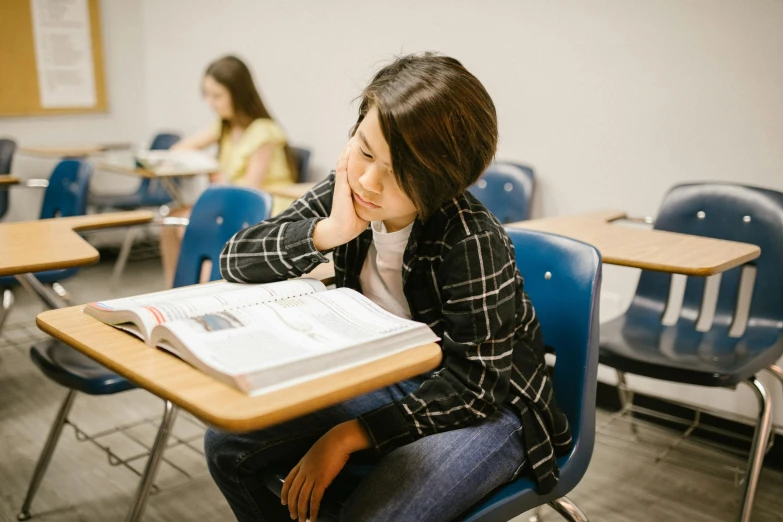 a woman sitting at a desk reading a book, by Jang Seung-eop, trending on pexels, academic art, sitting in the classroom, pouting, 15081959 21121991 01012000 4k, thumbnail