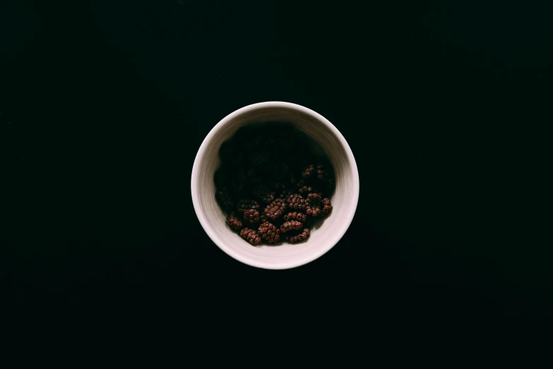 a close up of a bowl of food on a table, inspired by Elsa Bleda, unsplash, minimalism, coffee beans, out in the dark, ignant, white mug