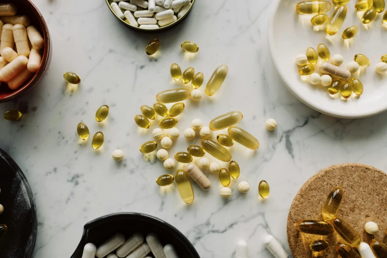 a table topped with lots of different types of pills, by Carey Morris, trending on pexels, renaissance, white and yellow scheme, manuka, goop, closeup of arms