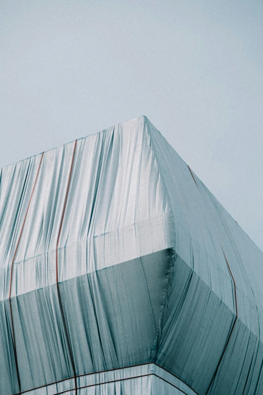 a man riding a snowboard on top of a snow covered slope, an abstract sculpture, inspired by Christo, unsplash contest winner, postminimalism, fully covered in drapes, artwork of a building, aluminum, white box