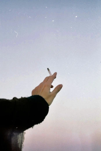a man that is holding a cigarette in his hand, an album cover, unsplash, visual art, instant photograph of the sky, 1990s photograph, ignant, mina petrovic