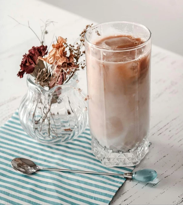 a glass of coffee sitting on top of a table, moonstone, profile image, milkshake, cottagecore hippie