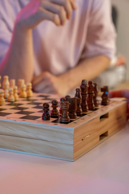 a person playing a game of chess on a table, zoomed in, wooden casing, connectivity, close together