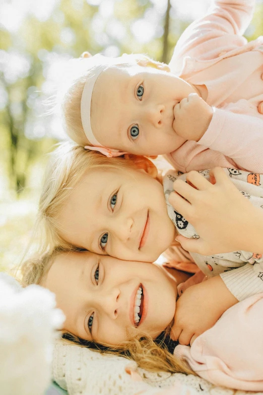 a couple of little girls laying on top of each other, a picture, by Anna Füssli, shutterstock, portrait of family of three, heterochromia, soft portrait shot 8 k, a blond