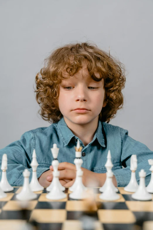 a young boy sitting at a chess board, trending on unsplash, on grey background, curls on top, ignant, on white background