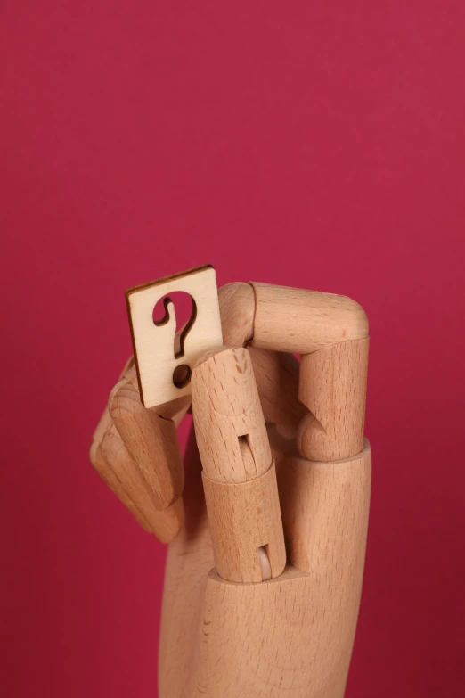 a hand holding a wooden block with a question mark on it, by James Morris, pink, single figure, thumbnail, wooden