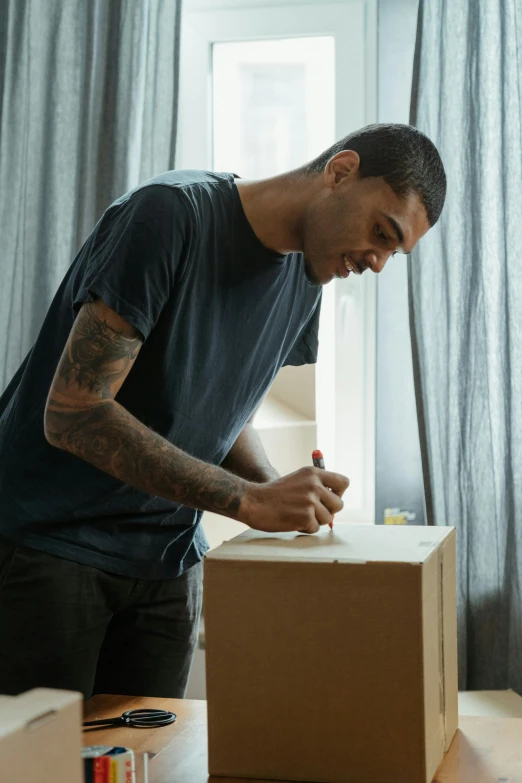 a man standing next to a box on top of a table, sharpie, location in a apartment, profile image, tattooed