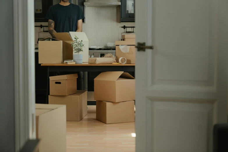 a man standing in a kitchen surrounded by boxes, pexels contest winner, hurufiyya, french provincial furniture, moving poetry, desks, inside of a bedroom