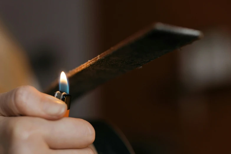 a person holding a lighter in their hand, an album cover, trending on pexels, bog oak, spatula, clean detail 4k, candle