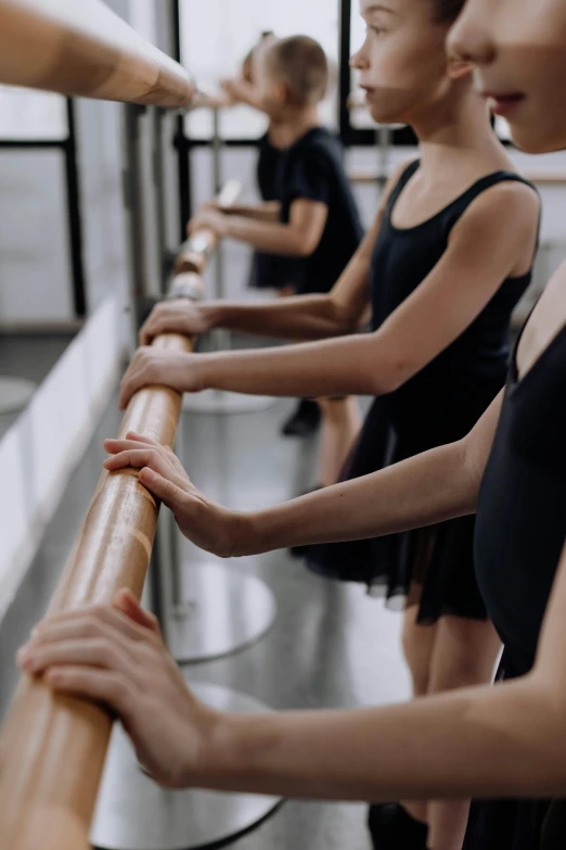 a group of young girls standing next to each other, arabesque, sleek hands, bench, standing in class, black